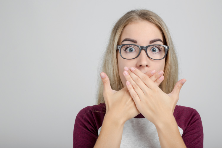 Blonde woman covers her mouth in embarrassment due to poor oral hygiene and gum disease